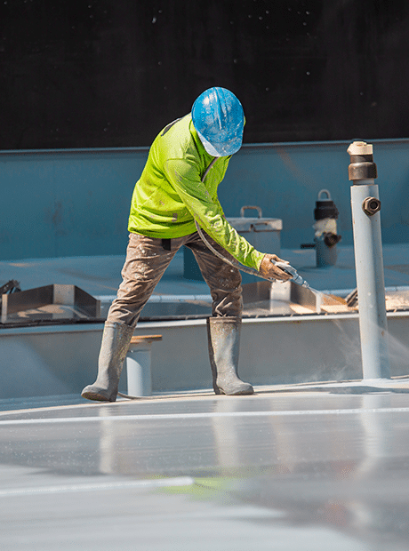 Technician spraying commercial roof coating.