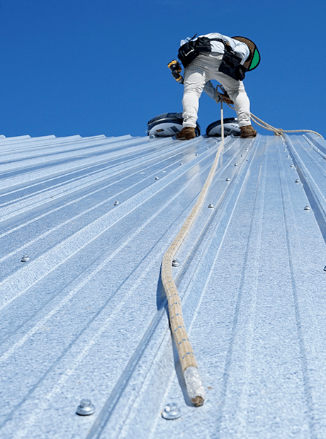 Technician installing new metal roofing panels on home.